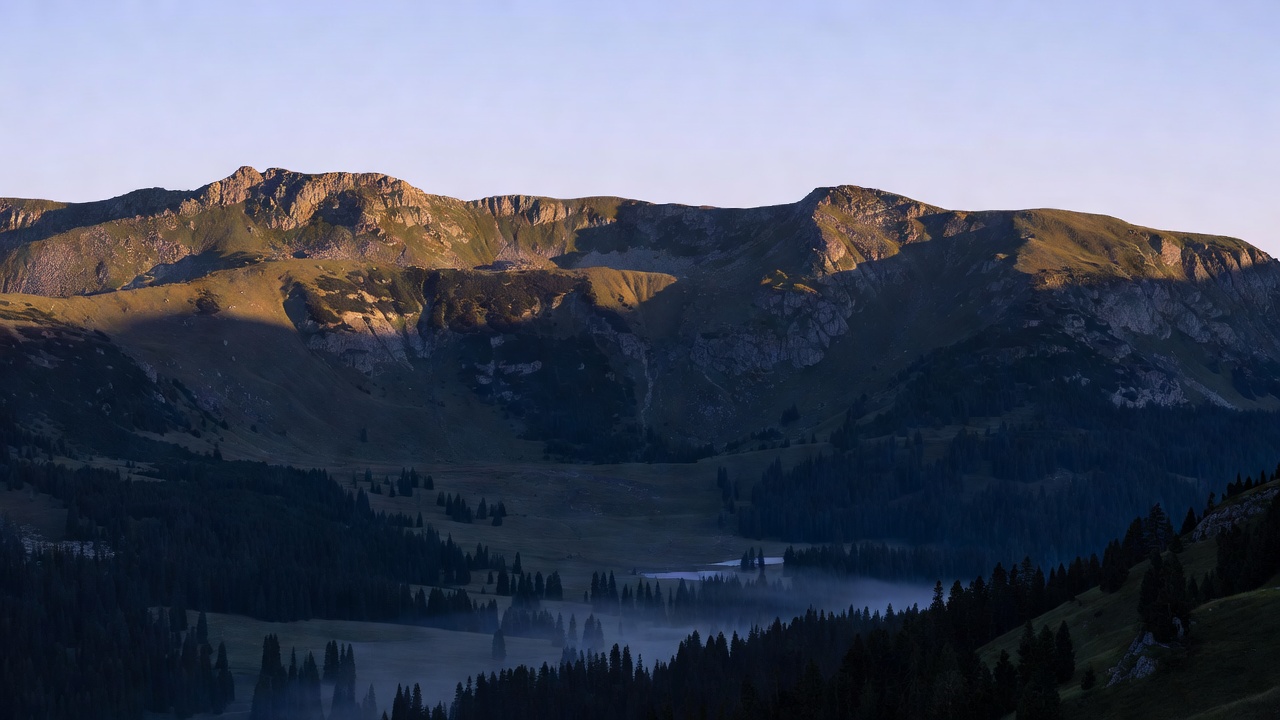 First warm light touching an alpine ridge while the valley remains in shadow